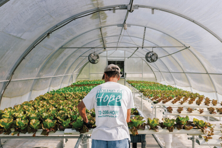 Phil Dakin wearing a Growing Hope Farm t-shirt inside one of the greenhouses
